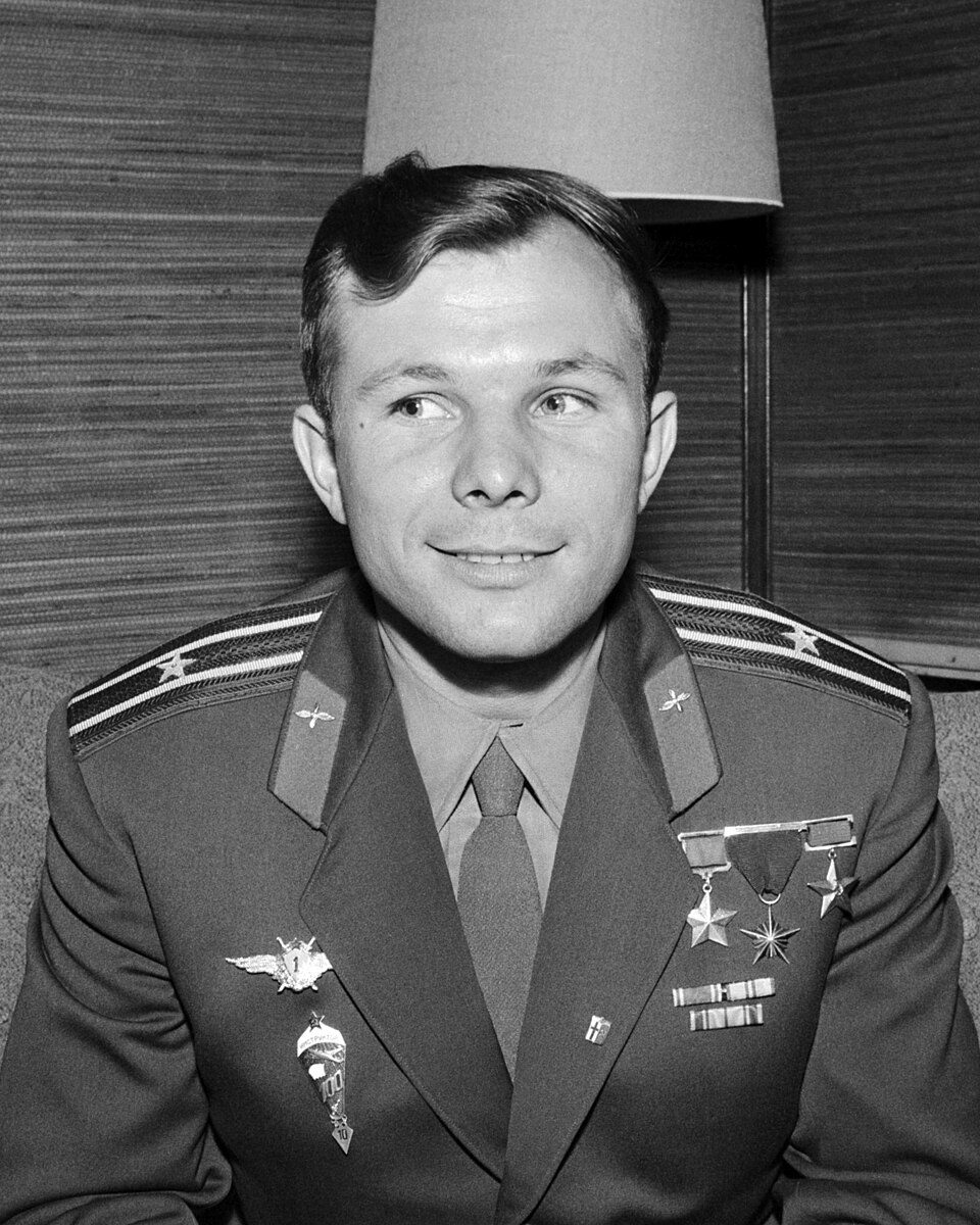 A black and white portrait of Yuri Gagarin in uniform, smiling.