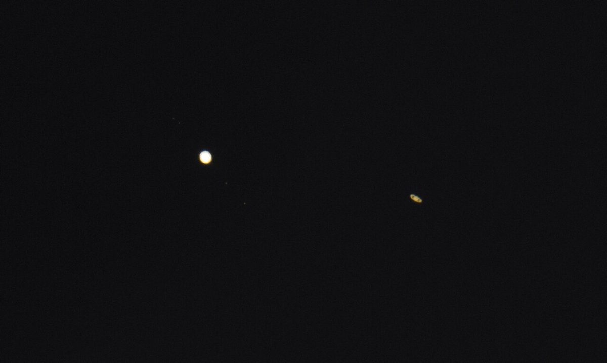 Jupiter and Saturn shine as two close bright points in a dark evening sky.