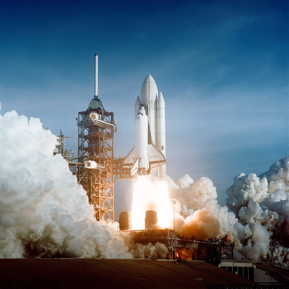 The Space Shuttle Columbia lifts off from Pad 39A amid billowing clouds of exhaust.