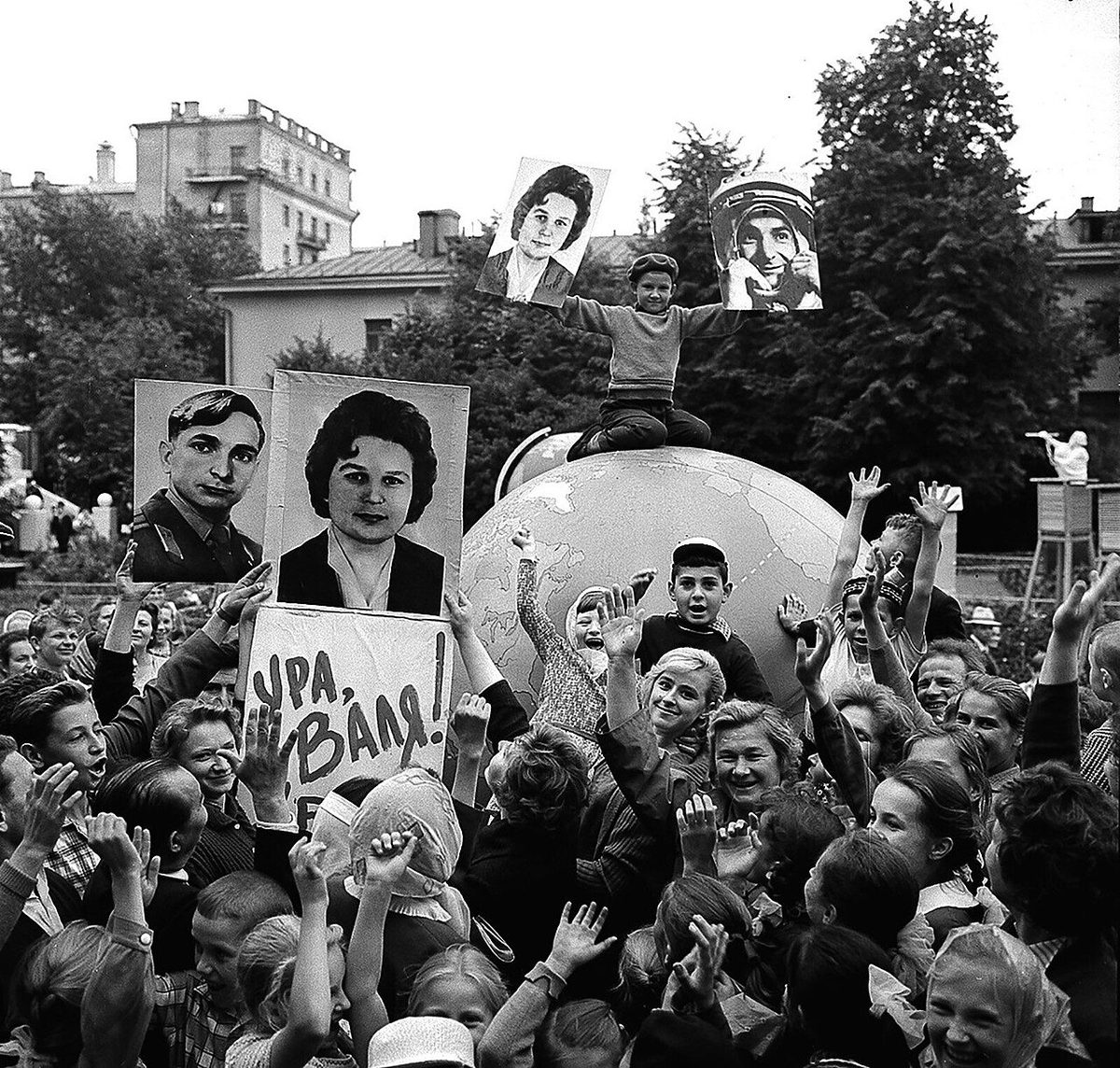 A cheering crowd in Moscow holds up portraits of Valentina Tereshkova and signs saying Hurrah, Valya.