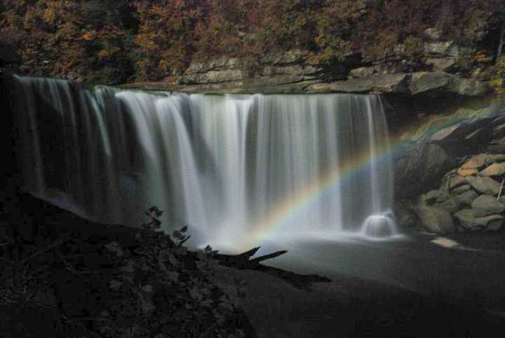 A pale moonbow arcs across the spray at the foot of Cumberland Falls on a moonlit night.