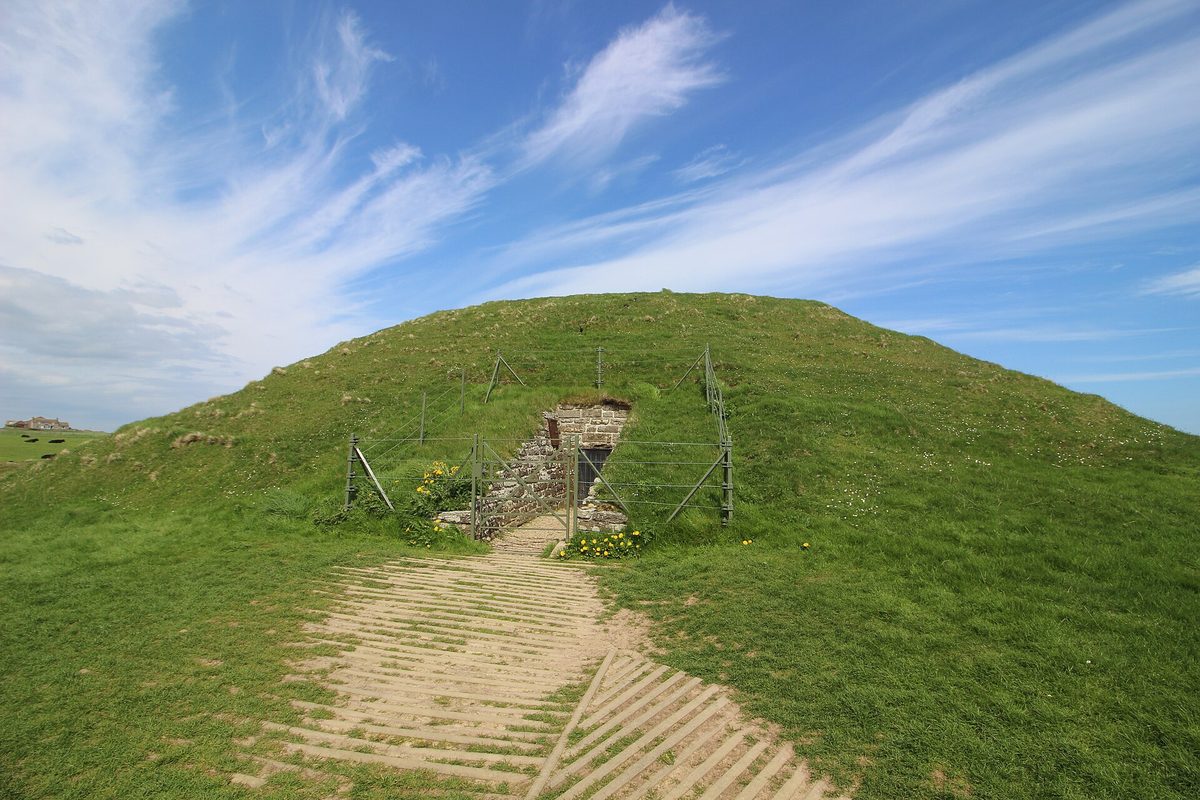 The grass-covered mound of Maeshowe on Orkney, with its stone-lined entrance passage, the passage the midwinter sunset shines down.