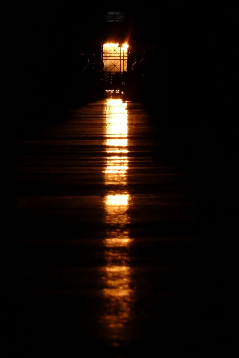 The setting Sun shines down the length of MIT's Infinite Corridor, laying a line of gold light along the dark floor.