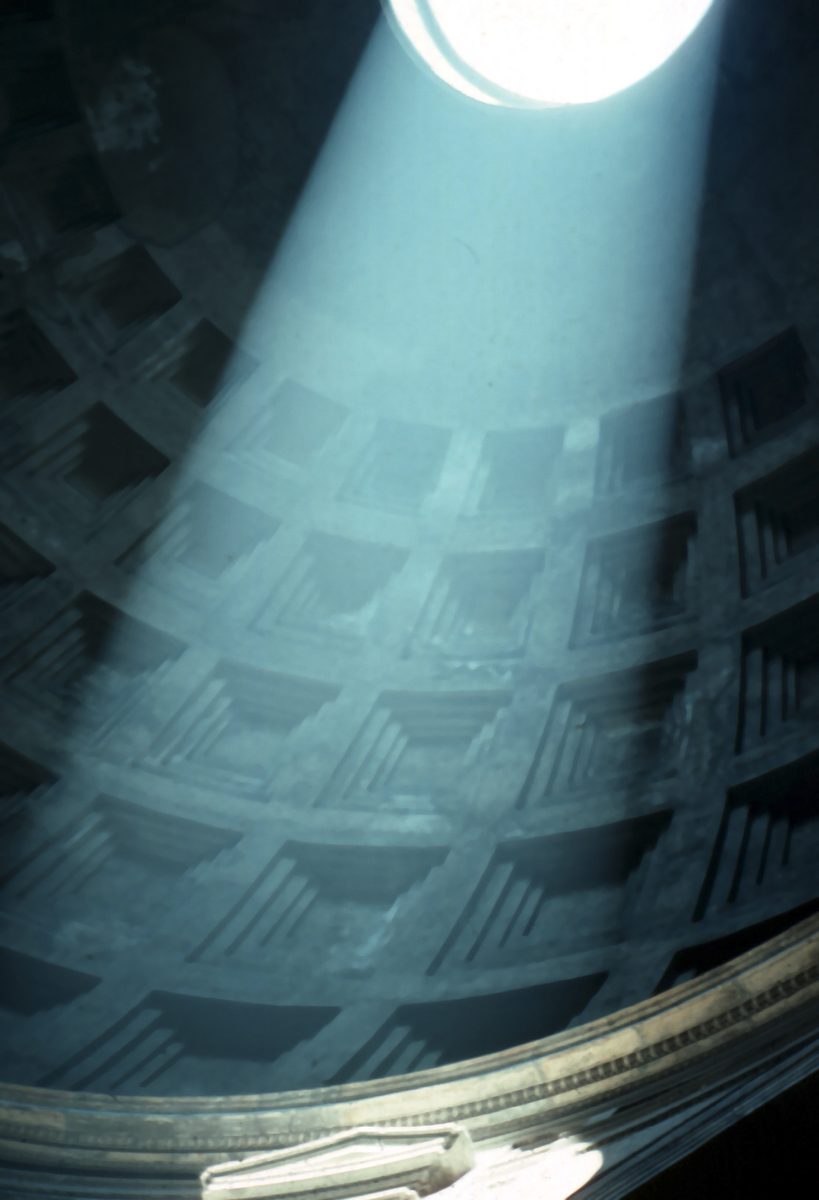 A beam of sunlight from the open oculus slants across the coffered dome inside the Pantheon in Rome.