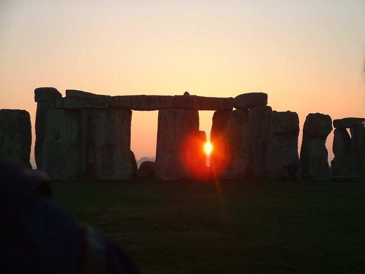 The setting Sun shines through the gap of a trilithon at Stonehenge near the winter solstice.